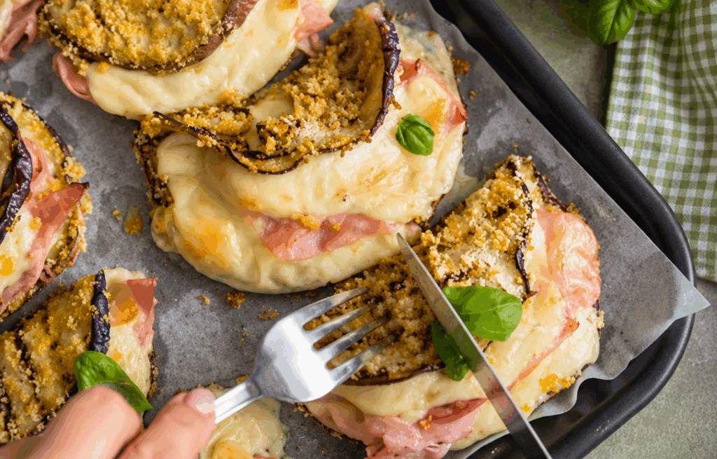 Ho messo prosciutto e formaggio tra due fette di melanzana, poi tutto in forno: niente frittura, vengono morbide dentro, croccantine sopra e il formaggio fila appena le apri